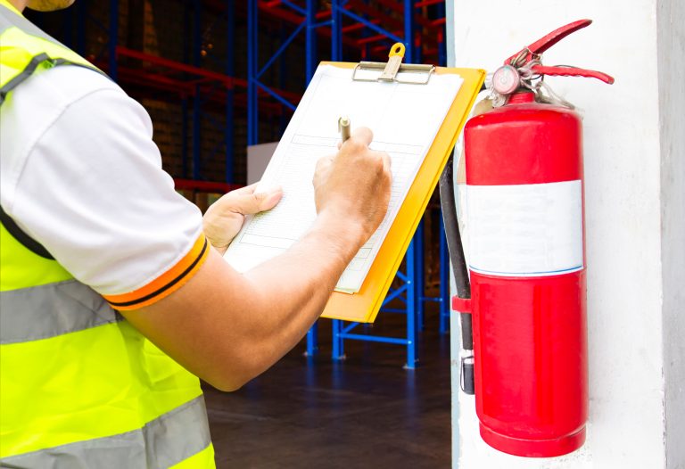 Profissional técnico verificando extintores para emitir laudo do Corpo de Bombeiros